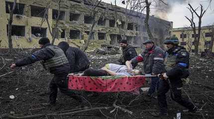 Ukrainian volunteers carry an injured pregnant woman from the damaged by shelling