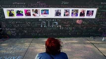 person visits a makeshift memorial near the scene of Saturday's shooting at a supermarket