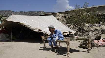 Afghan boy sits in a courtyard of her destroyed home after an earthquake