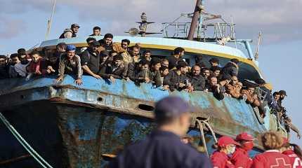 Migrants look out of a fishing boat