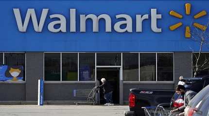 woman pushes a shopping cart to enter a Walmart