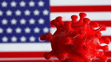 3D-printed coronavirus model is seen in front of a U.S. flag