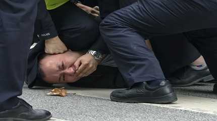 Policemen pin down and detain a protester