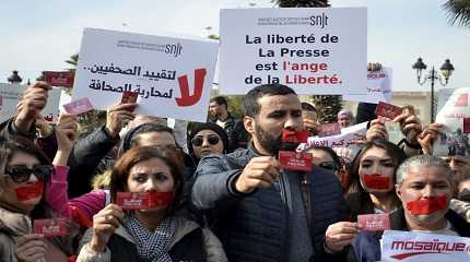 Gaged journalists show their press card as they protest