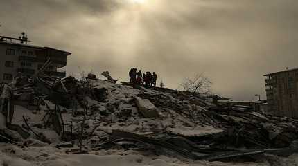 People try to reach people trapped under the debris