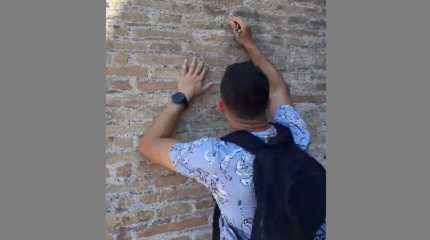 A tourist carves on the wall of the Colosseum in Italy 