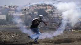 Palestinian demonstrator hurls back a tear gas