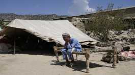 Afghan boy sits in a courtyard of her destroyed home after an earthquake