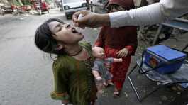 health worker gives a polio vaccine to a girl