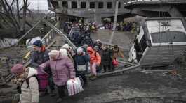 People cross destroyed bridge in Ukraine town