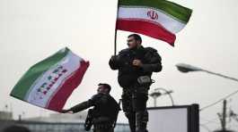 Two anti-riot police officers wave the Iranian flags