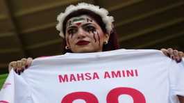 woman holds a jersey with the name of Mahsa Amini