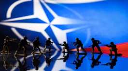 Army soldier figurines in front of the NATO logo