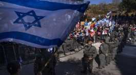 Protesters wave flags and hold banners against Benjamin Netanyahu
