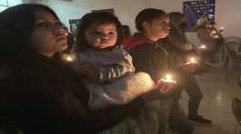 migrants participate in a candle lighting ceremony of Christmas