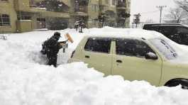 resident shovels snow off around a car