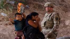 Migrants stand near the Rio Bravo river