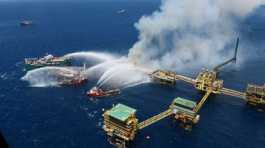 Boats spray water onto an offshore oil platform