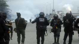 Police officers disperse protesters with tear gas