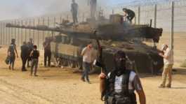 Hamas fighters with burnt Israeli tank