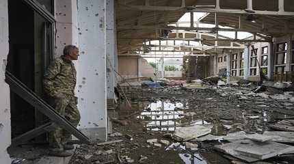 Ukrainian serviceman looks at the ruins of the sports complex