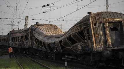 railway worker stands next to heavily damaged train after a Russian attack