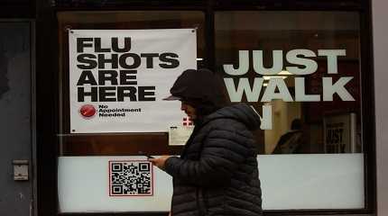 A man walks past an urgent care facility offering flu shots