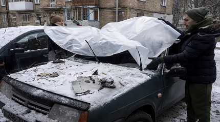 couple cover their damaged car after a Russian attack