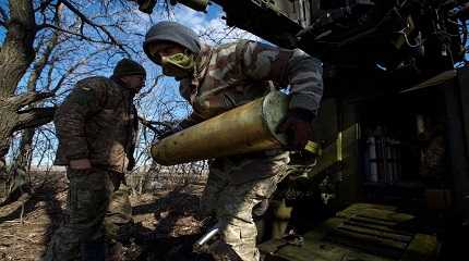 Ukrainian serviceman carries a shell for a 2S5