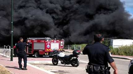 Israeli policemen stand next to smoke from a fire