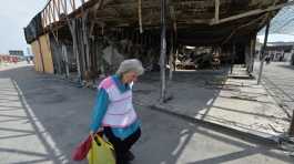 woman walks past a destroyed shop